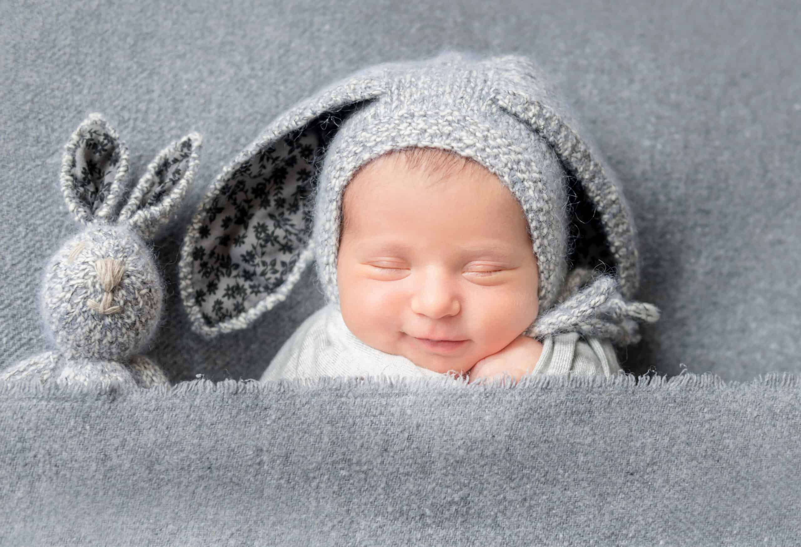 Sleeping baby with grey bunny ears and bunny next to him