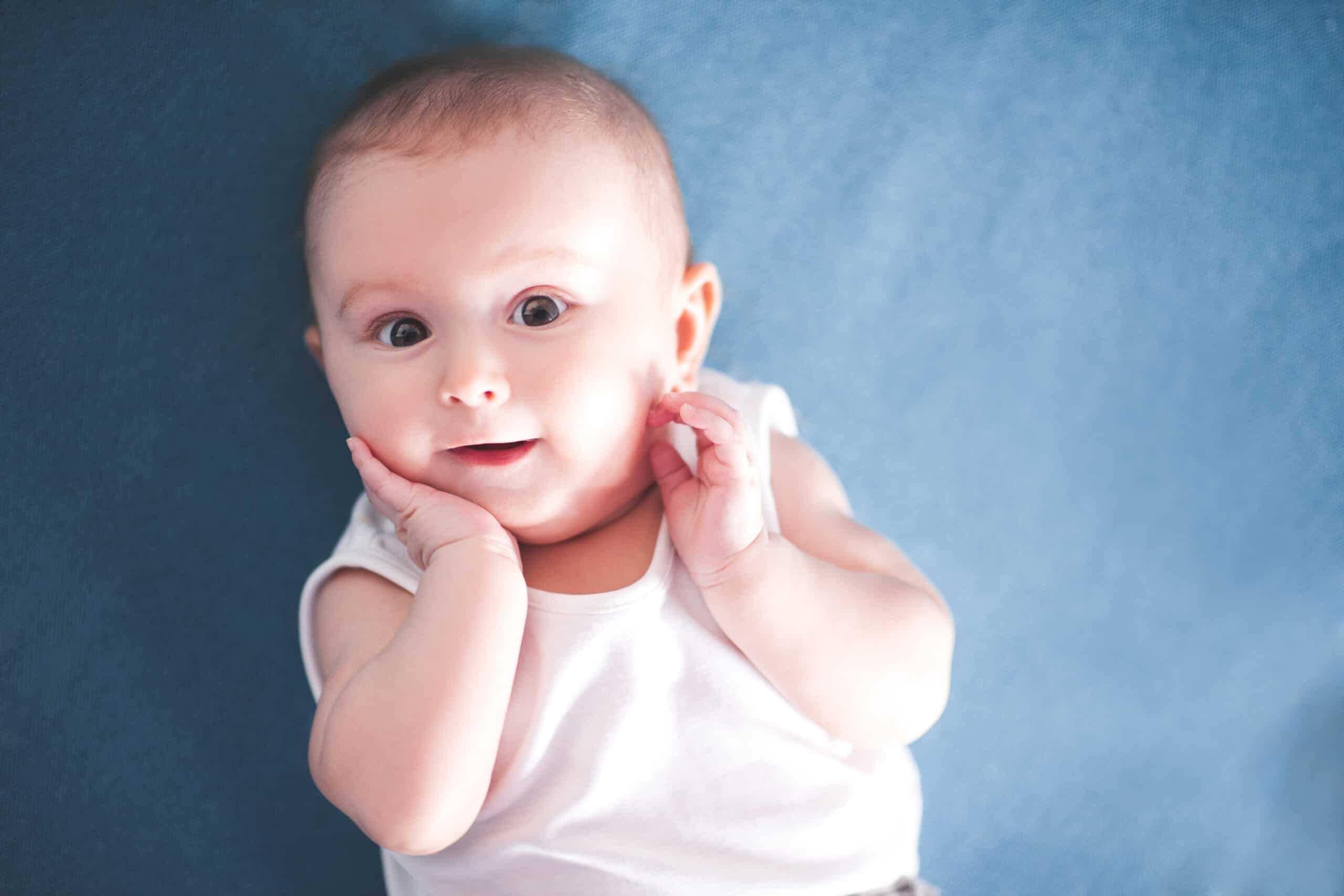 cute baby with big eyes and hands on face