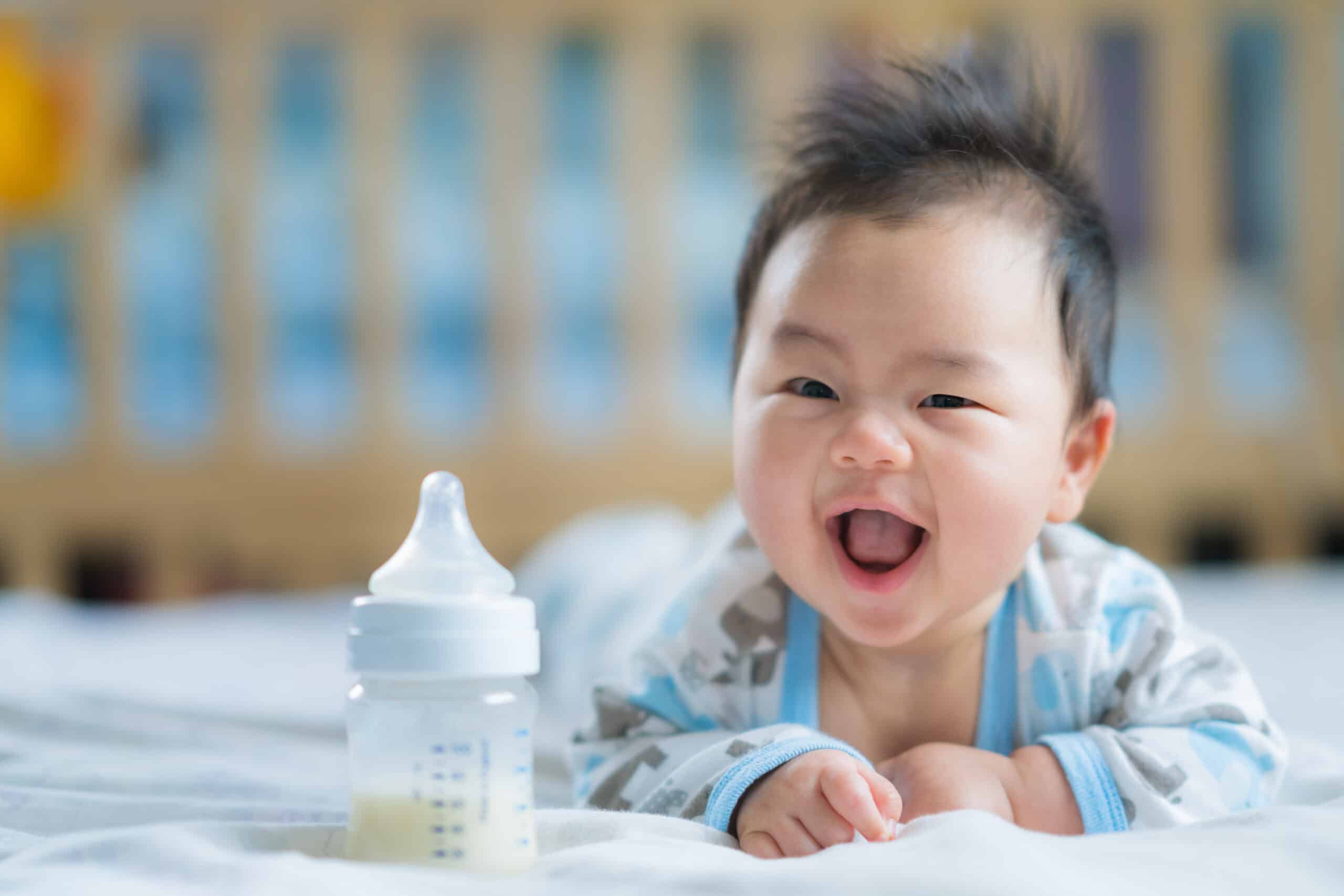 Cute baby on his tummy with a bottle next to him