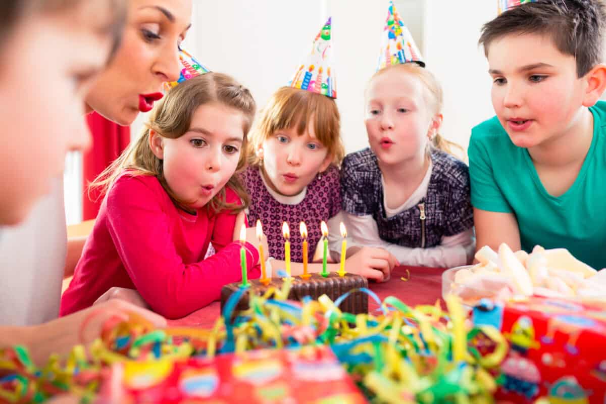Child blowing candles out on a birthday cake.