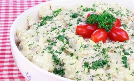 Large bowl of homemade potato salad with grape tomatoes. Garnished with fresh parsley.