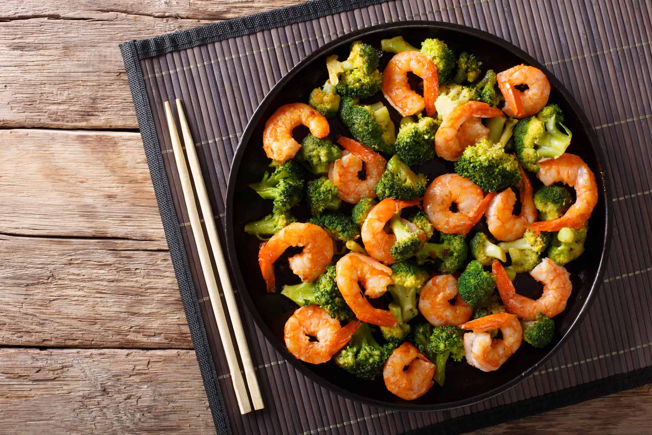 Stir frying shrimp with broccoli closeup on a plate. Horizontal top view from above