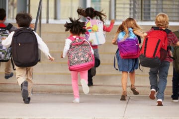 Kids with backpacks running into school