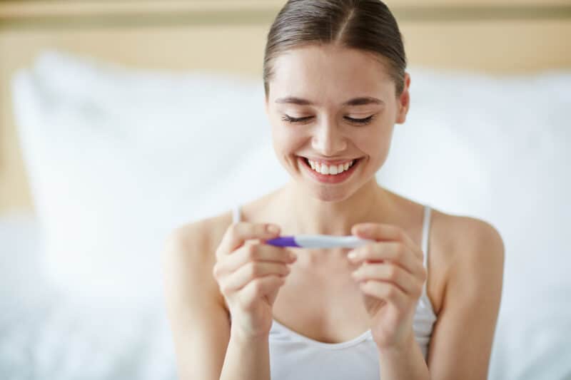 Newly pregnant woman holding pregnancy test.