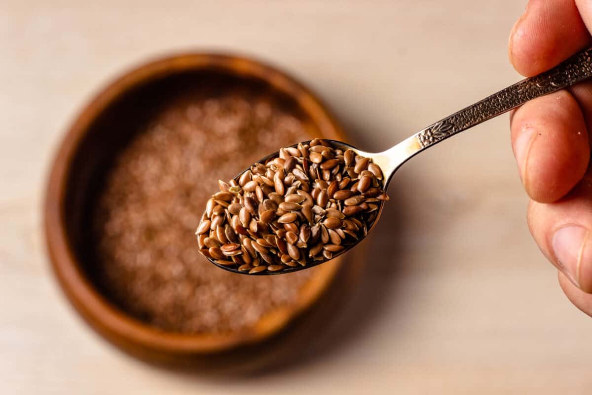 Old-Fashioned Cranberry Bread can be made with flax seeds as an egg replacement - Down of flax seeds blurred below a close-up of a spoon full of flaxseed