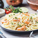 Italian pasta fettuccine in a creamy sauce with shrimp on a plate, close-up.