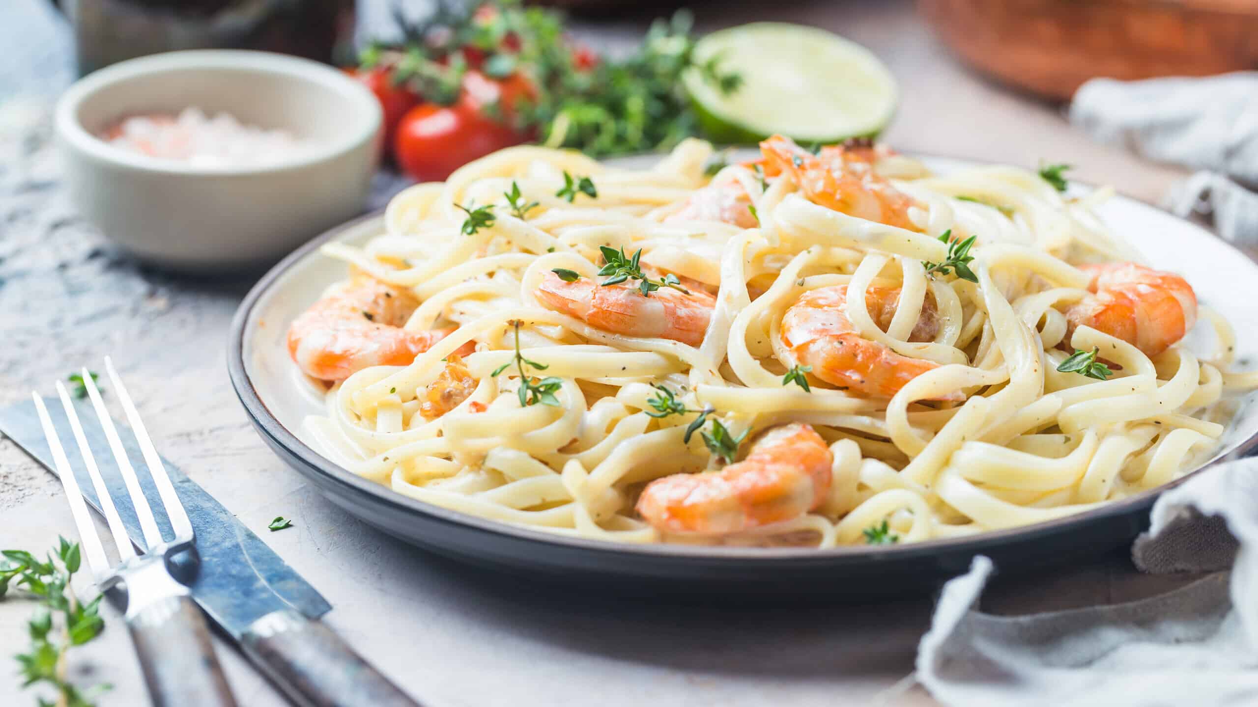 Italian pasta fettuccine in a creamy sauce with shrimp on a plate, close-up.