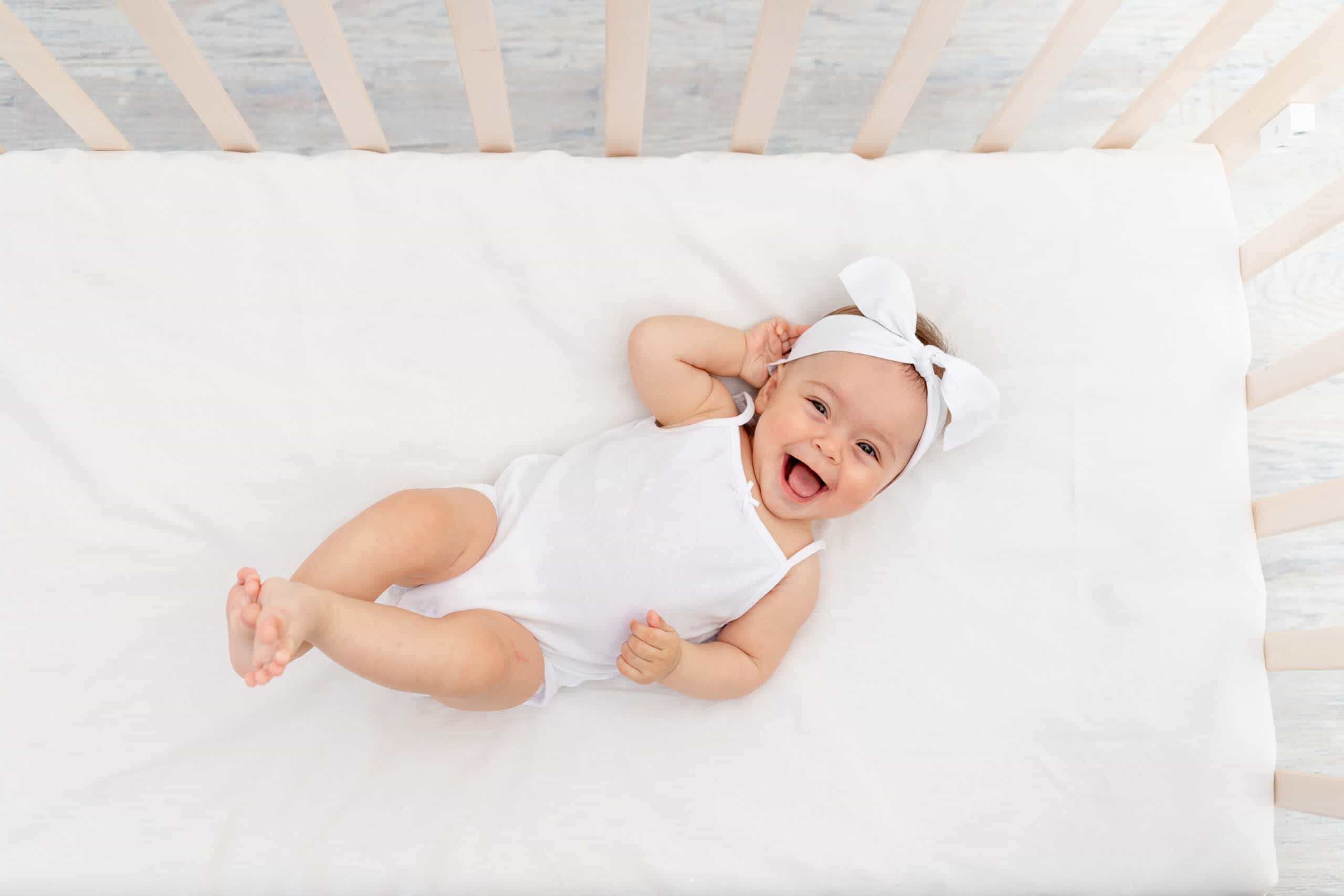 smiling baby in crib laying on her back