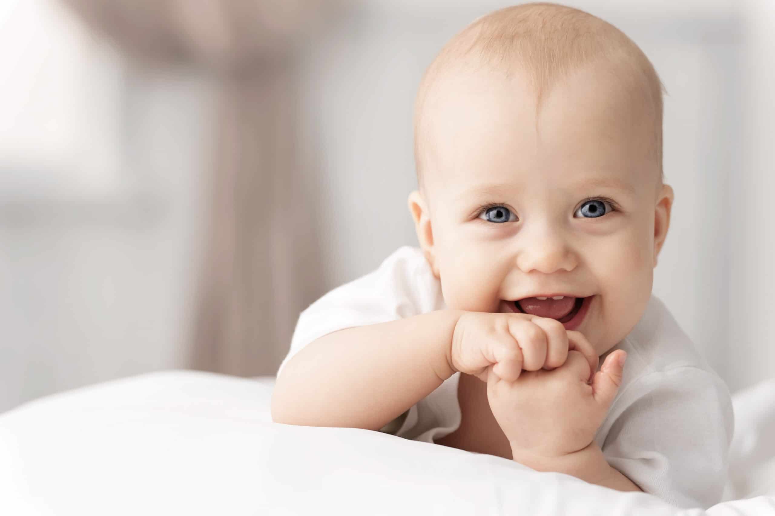 happy baby smiling with fingers in mouth