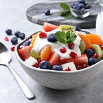 Delicious fruit salad with yogurt on grey table