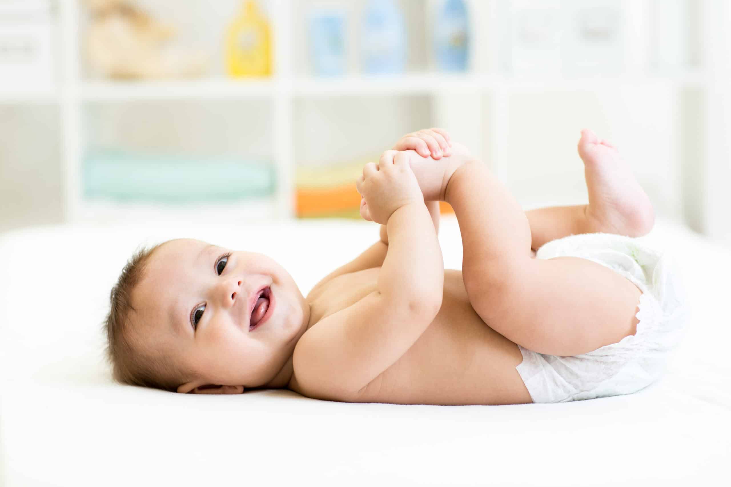 baby laying her back holding her foot