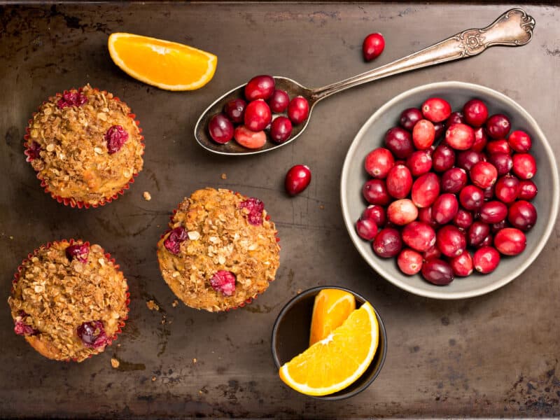 Cranberry nut muffins next to cranberries and orange slices