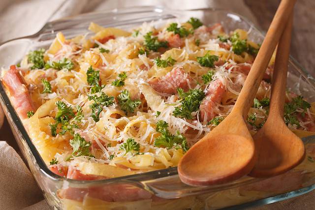 Austrian noodles with ham and parmesan close-up in a glass baking dish on the table