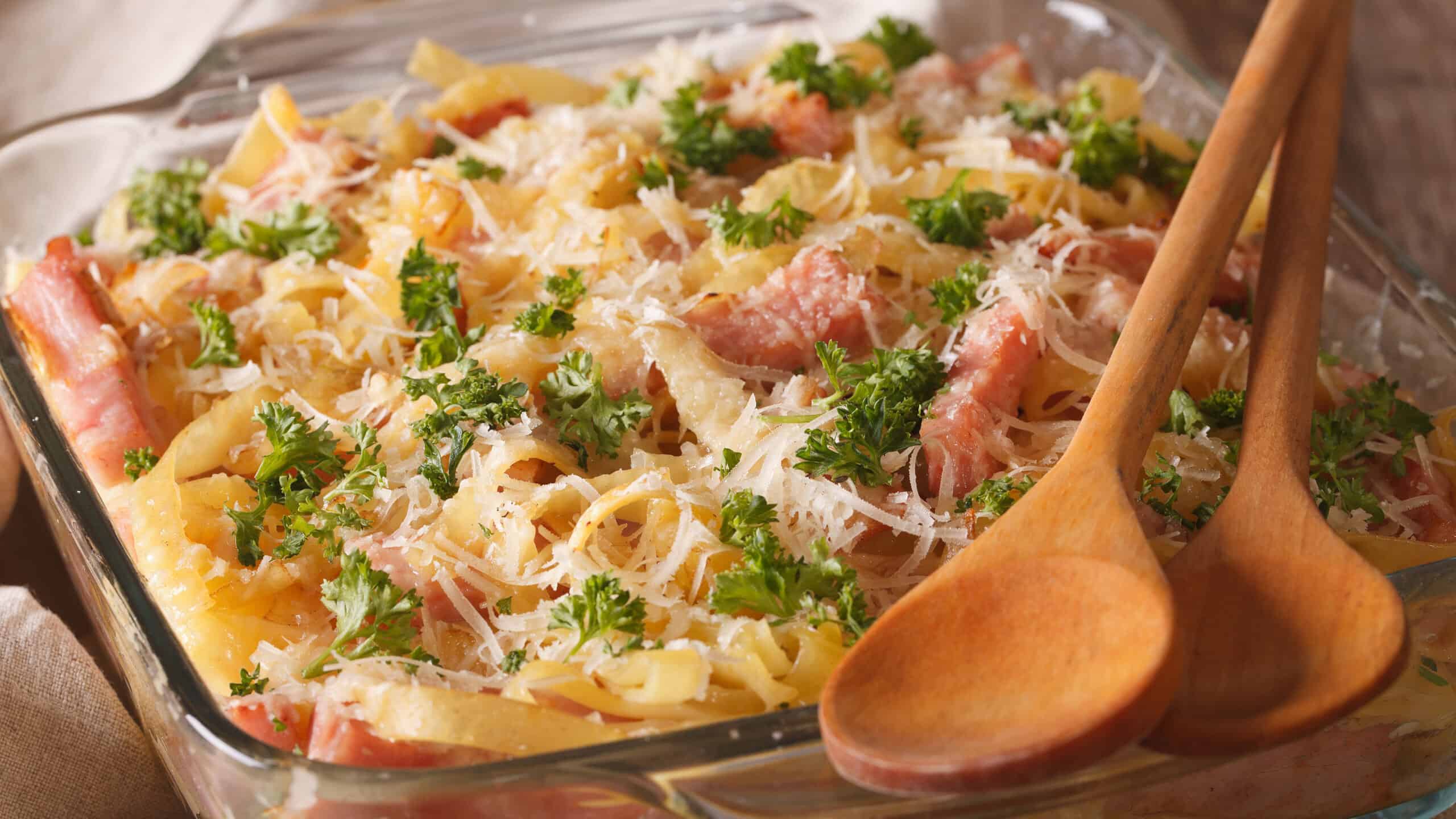 Austrian noodles with ham and parmesan close-up in a glass baking dish on the table