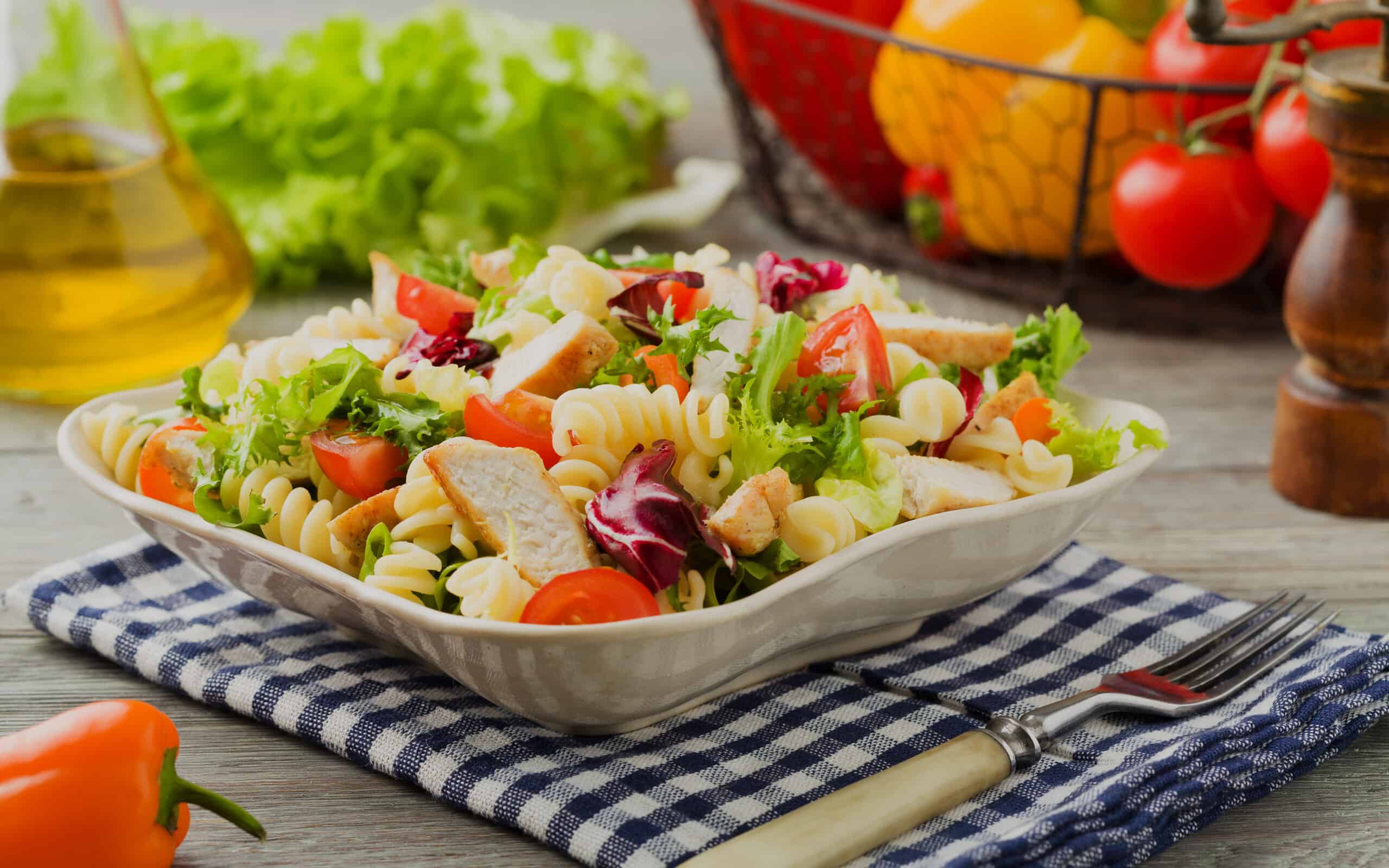 Delicious pasta salad with green lettuce, tomatoes and roasted chicken.