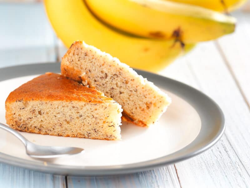 Yellow cake mix banana bread served on a china plate with fresh bananas in the background.