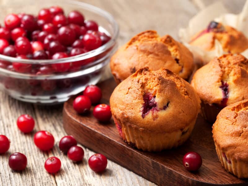 Cranberry muffins pictured with a bowl of fresh cranberries