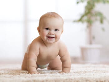 Sweet baby with big smile crawling on the floor.