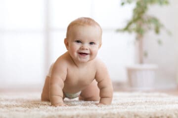 Sweet baby with big smile crawling on the floor.